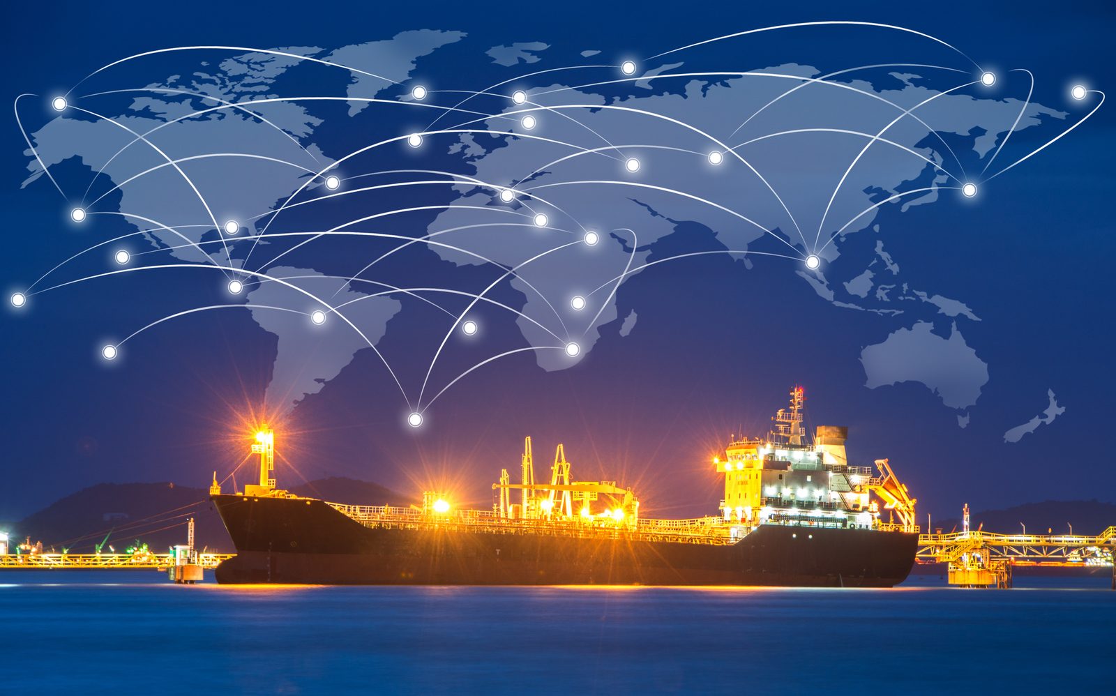 Cargo ship at a lit port terminal at night